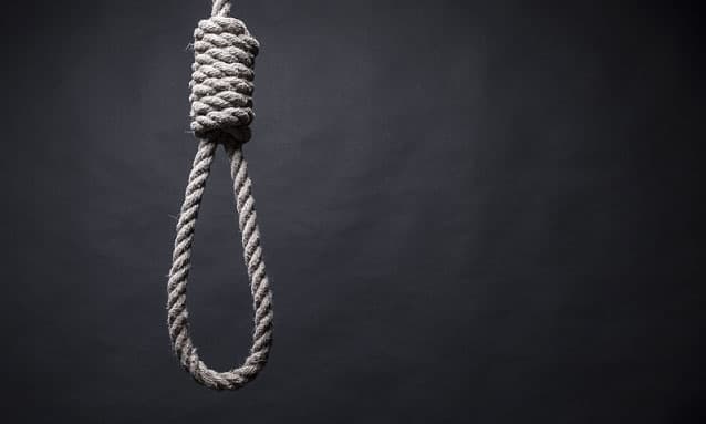 A thick rope hangman's noose with a large knot hanging against a dark, textured background.